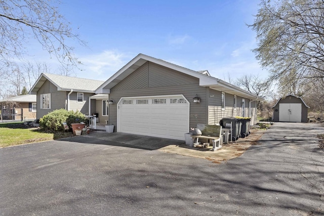 view of property exterior with an outdoor structure, a garage, driveway, and a shed