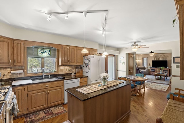 kitchen featuring decorative backsplash, a sink, white appliances, and a kitchen island
