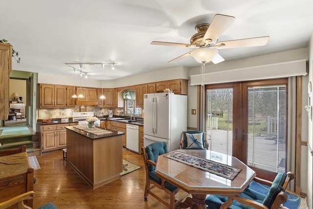 kitchen with white appliances, french doors, a ceiling fan, a kitchen island, and dark countertops