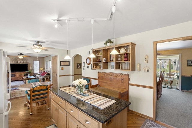 kitchen featuring track lighting, arched walkways, ceiling fan, freestanding refrigerator, and dark wood finished floors