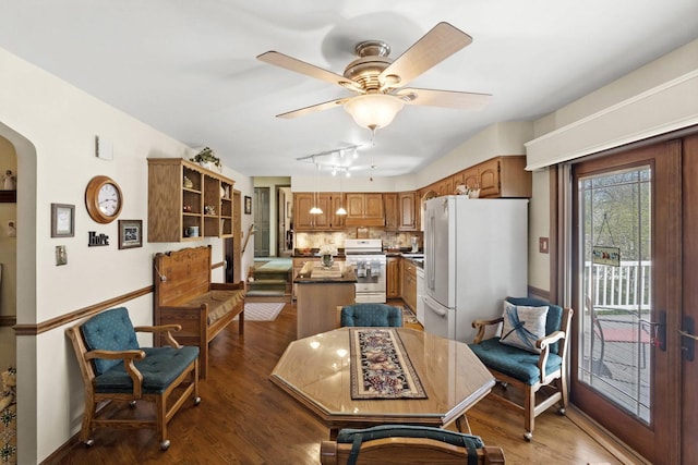 dining space with arched walkways, baseboards, a ceiling fan, and dark wood finished floors