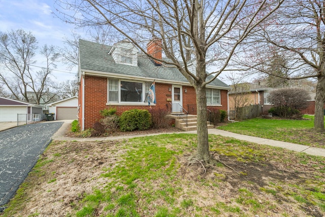 view of front of house featuring an outbuilding, a garage, fence, brick siding, and a front lawn