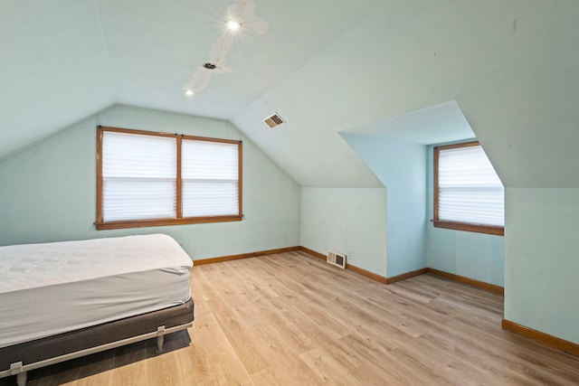 bedroom featuring visible vents, baseboards, vaulted ceiling, and wood finished floors