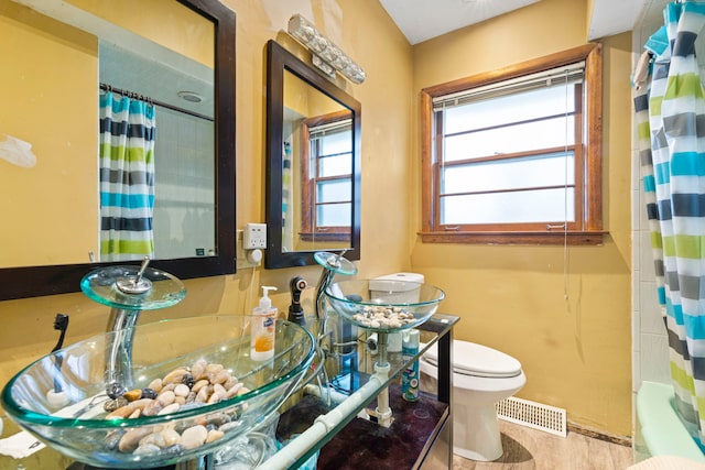 bathroom featuring shower / bath combination with curtain, visible vents, a sink, and toilet