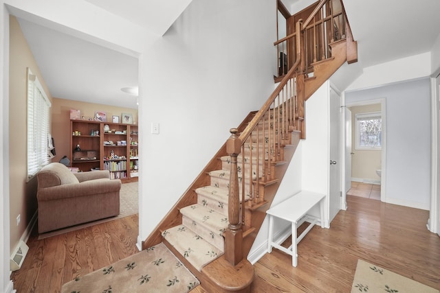 stairway with baseboards, wood finished floors, and visible vents