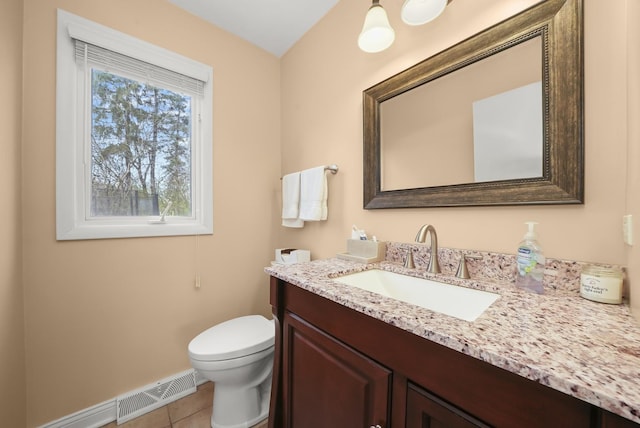 half bathroom with tile patterned flooring, vanity, toilet, baseboards, and visible vents