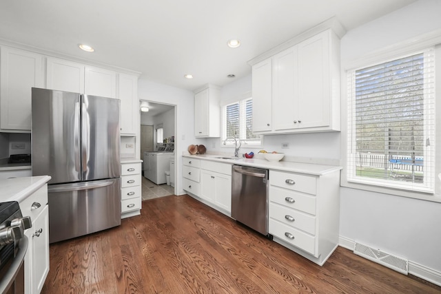 kitchen featuring appliances with stainless steel finishes, a sink, light countertops, washer / clothes dryer, and visible vents