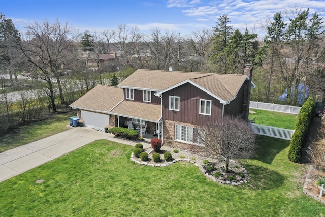 traditional-style house featuring fence, a chimney, driveway, and a front yard