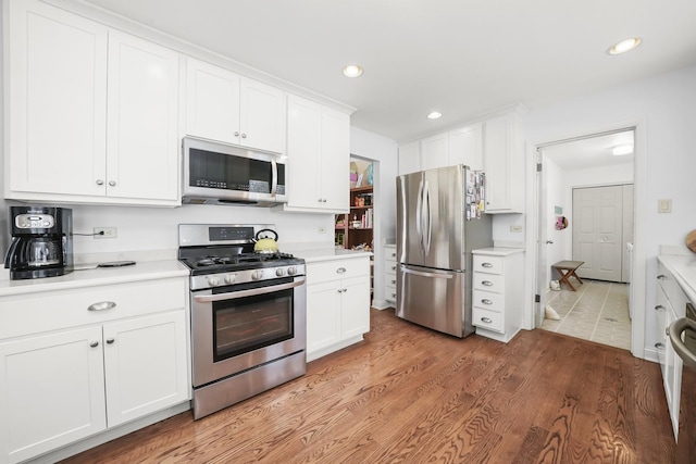 kitchen with light wood-style floors, light countertops, white cabinets, and stainless steel appliances