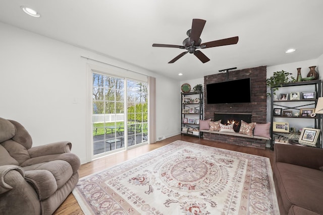 living area featuring a brick fireplace, recessed lighting, ceiling fan, and wood finished floors