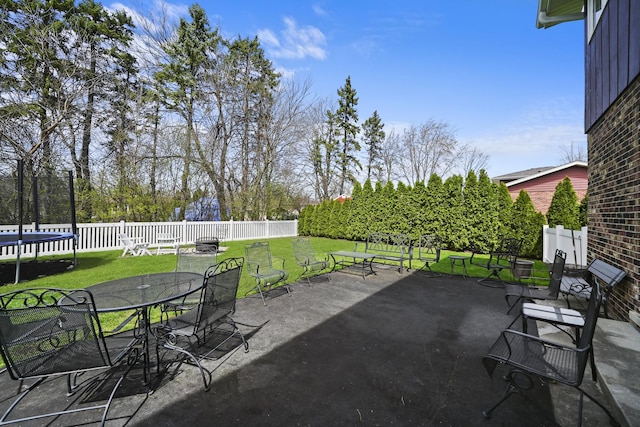 view of patio / terrace with outdoor dining area, a fenced backyard, and a trampoline