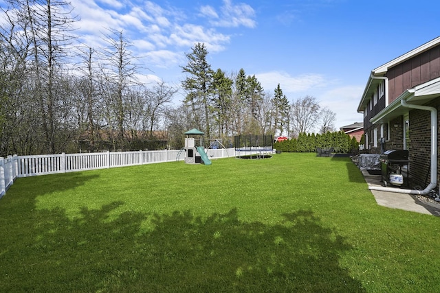 view of yard featuring a fenced backyard, a trampoline, and a playground