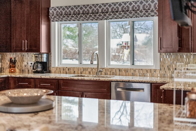 kitchen with stainless steel dishwasher, dark brown cabinetry, a sink, and backsplash