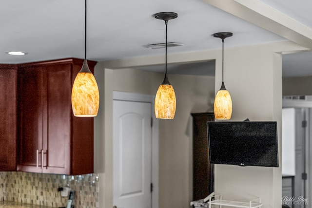 kitchen featuring decorative light fixtures, decorative backsplash, dark brown cabinets, and visible vents