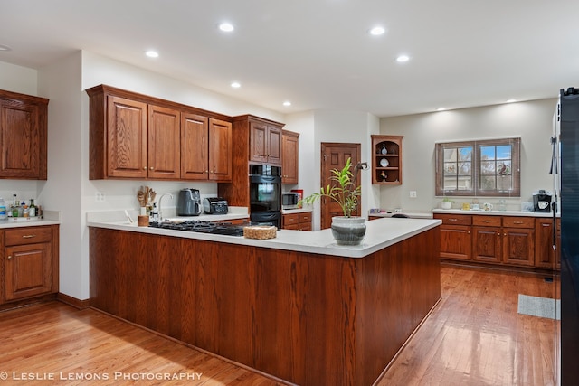 kitchen featuring open shelves, light countertops, a peninsula, recessed lighting, and light wood finished floors