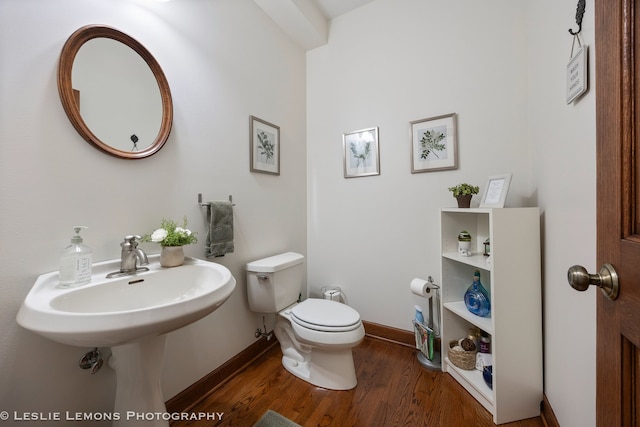 bathroom with toilet, wood finished floors, and baseboards