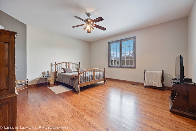 bedroom featuring light wood-style floors, baseboards, visible vents, and ceiling fan