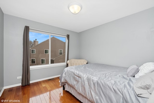 bedroom with wood-type flooring, visible vents, and baseboards
