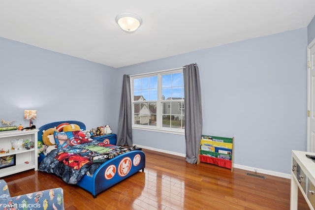 bedroom featuring visible vents, baseboards, and wood finished floors