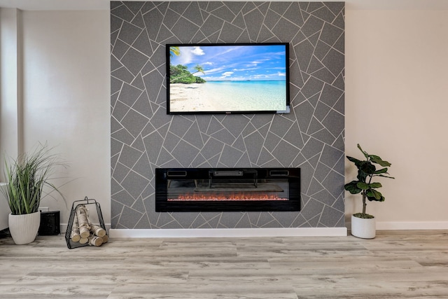room details with baseboards, wood finished floors, an accent wall, and a tile fireplace