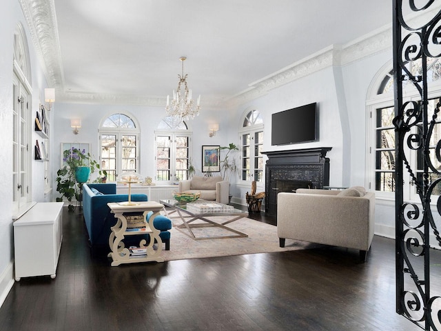 living room featuring crown molding, a fireplace, dark wood-style floors, a chandelier, and french doors