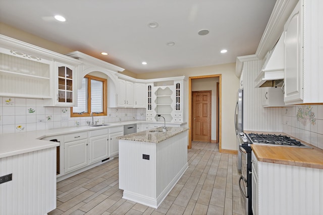kitchen with backsplash, stainless steel appliances, open shelves, and a sink