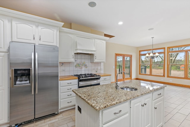 kitchen with an inviting chandelier, custom exhaust hood, tasteful backsplash, a sink, and appliances with stainless steel finishes