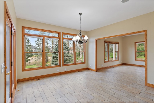 unfurnished room with a chandelier, baseboards, and visible vents