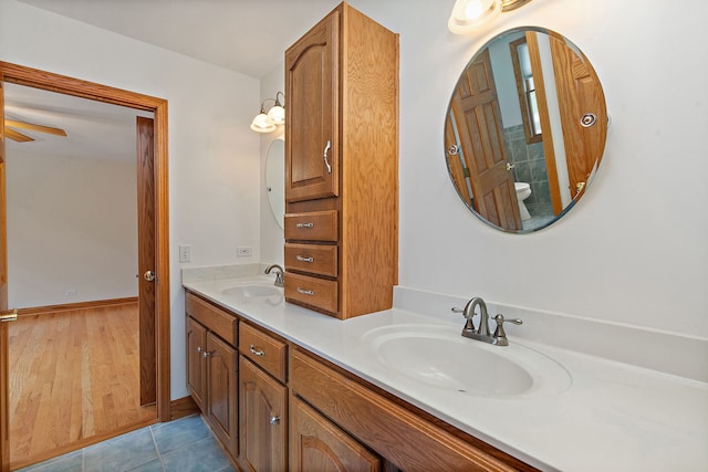 bathroom featuring double vanity, a sink, a ceiling fan, and toilet