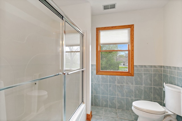 full bath with wainscoting, tile patterned flooring, toilet, tile walls, and visible vents
