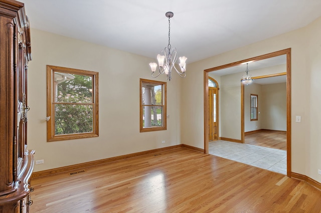 unfurnished room with light wood-style floors, baseboards, a chandelier, and visible vents