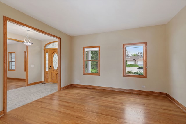 entryway with a healthy amount of sunlight, an inviting chandelier, light wood-type flooring, and visible vents