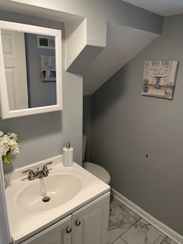 bathroom with vanity, marble finish floor, baseboards, and visible vents