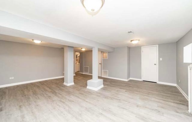 finished basement with visible vents, baseboards, and wood finished floors