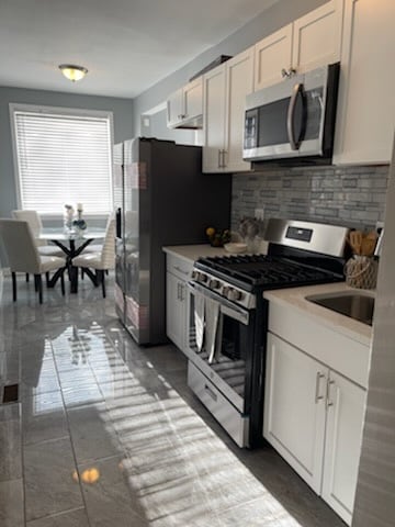 kitchen featuring white cabinets, backsplash, and appliances with stainless steel finishes