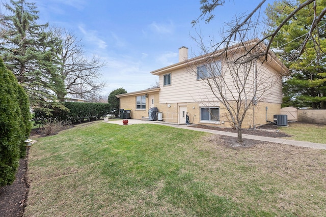 rear view of property featuring cooling unit, a yard, a patio, fence, and a chimney