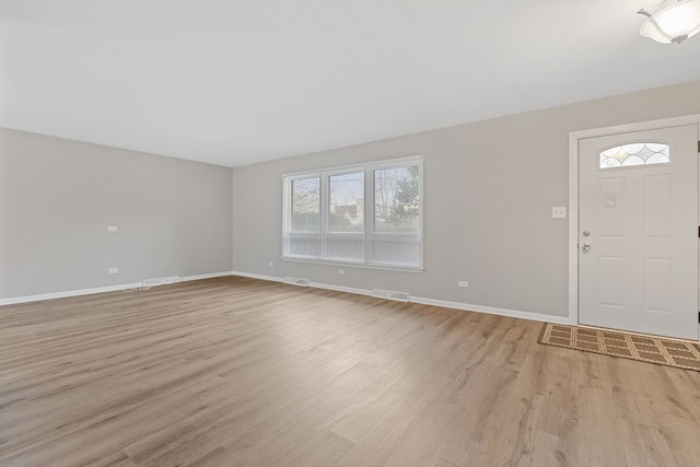 foyer entrance with light wood-style floors, baseboards, and visible vents