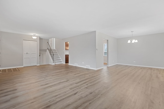 unfurnished living room featuring light wood-type flooring, baseboards, a chandelier, stairway, and visible vents