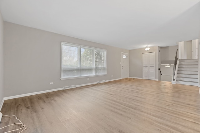 unfurnished living room with stairway, visible vents, baseboards, and light wood-style flooring