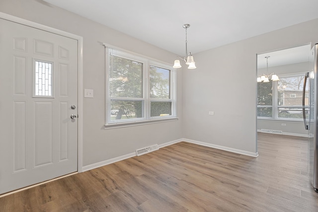foyer entrance featuring a chandelier, visible vents, baseboards, and wood finished floors