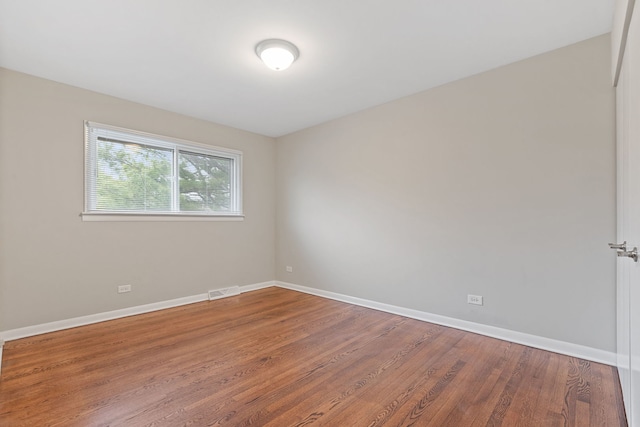 empty room with visible vents, baseboards, and wood finished floors