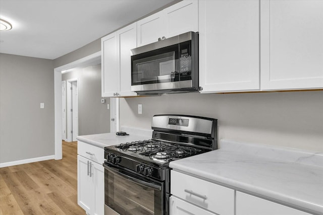 kitchen featuring white cabinetry, stainless steel microwave, light wood-type flooring, and gas stove
