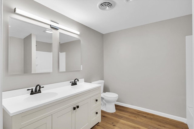 bathroom featuring toilet, wood finished floors, a sink, and visible vents