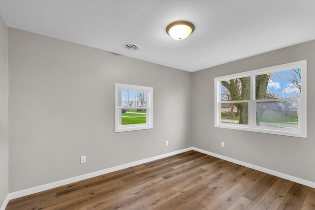unfurnished room with visible vents, baseboards, and wood finished floors