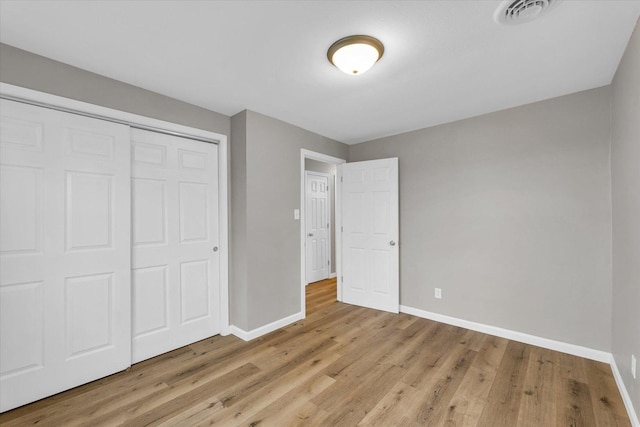 unfurnished bedroom with visible vents, baseboards, light wood-type flooring, and a closet