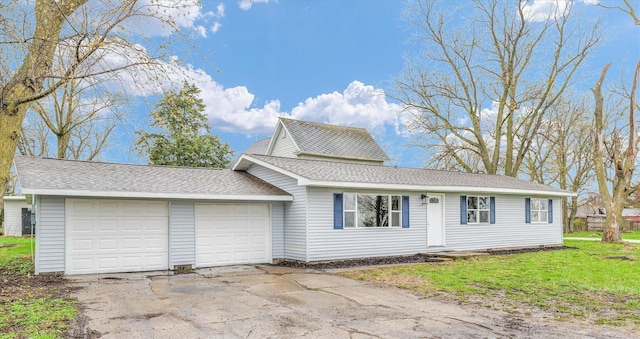 view of front of house featuring a front yard, an attached garage, a shingled roof, and driveway