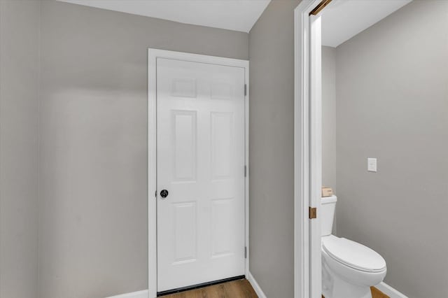 bathroom with baseboards, toilet, and wood finished floors