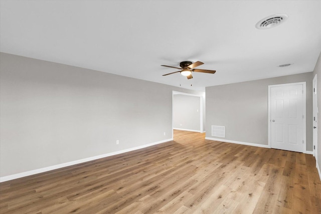 spare room featuring light wood-style flooring, visible vents, baseboards, and a ceiling fan