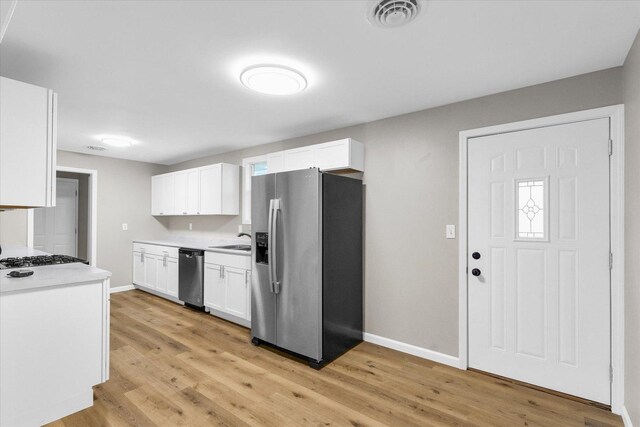 kitchen featuring visible vents, baseboards, white cabinetry, and stainless steel appliances
