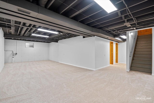 finished below grade area featuring stairway, visible vents, and carpet flooring
